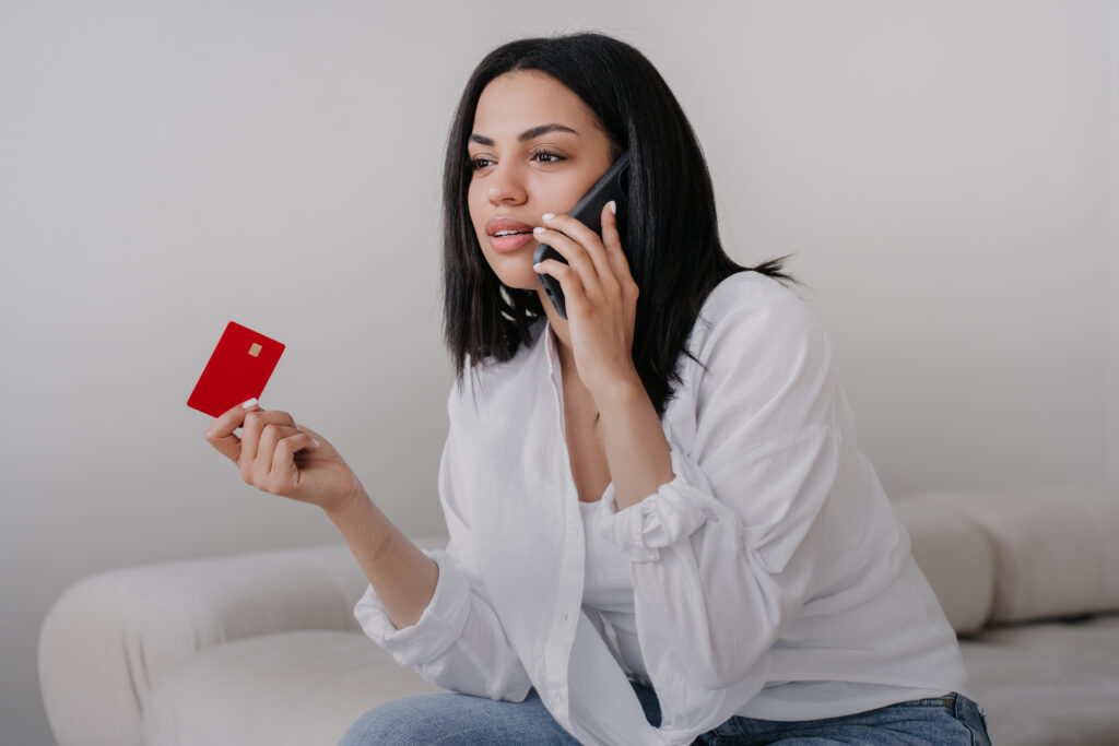 Mulher ao telefone segurando cartão bancário